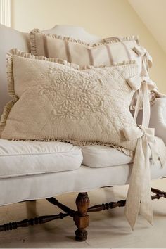 a white couch with pillows on top of it and a pillow tied to the back