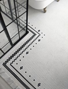 a white bath tub sitting next to a black and white tiled floor