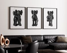 three black and white pictures hang on the wall above a couch in a living room