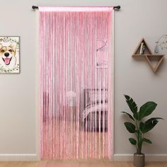 a pink curtain hanging on the side of a wall next to a potted plant