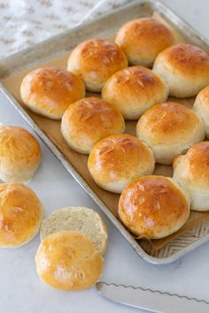 bread rolls sitting on top of a baking pan next to some slices of bread in front of them