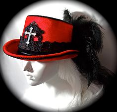 "This Gothic top hat is heavy red velvet wrapped with a black velvet and lace hatband and has a soft black crushed tulle bow & long tails in back. This Victorian style riding hat has black satin roses centered in the back. There is a silver antiqued Celtic cross centered on a beautiful black lace applique on the front of the crown. A black lace applique rests on the back of the crown's top. The brim & crown edge are trimmed in black satin braid. This hat is loaded with black curled ostri Black Curls, Custom Headbands, Tulle Bow, Gothic Tops, Velvet Hat, Tulle Bows, Riding Hats, Kentucky Derby Hat, Satin Roses