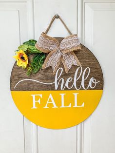 a wooden sign that says hello fall with sunflowers hanging on the front door