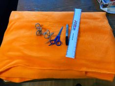 scissors and other items are sitting on an orange blanket