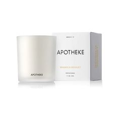 a white candle sitting next to a box on top of a white surface with the words apothheke in it