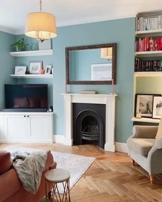 a living room filled with furniture and a fire place next to a book shelf on top of a hard wood floor