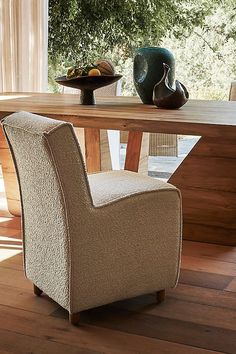 a chair sitting in front of a wooden table with vases on top of it