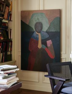 a painting on the wall next to a chair and bookshelf