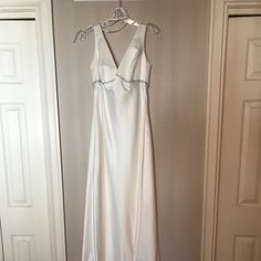 a white dress hanging on a hanger next to a door with a closet in the background