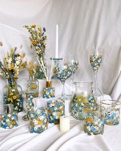 a table topped with vases filled with different types of flowers and candles next to each other