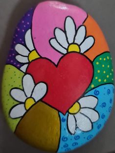 a painted rock with flowers and a heart on it