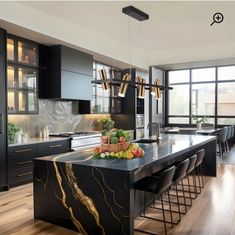 a modern kitchen with black cabinets and marble counter tops, an island in the center