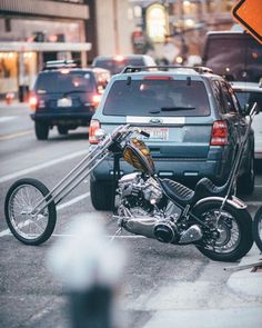 a motorcycle is parked on the side of the road near cars and a street sign