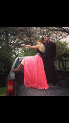 a man and woman standing in the back of a pick up truck with their arms outstretched