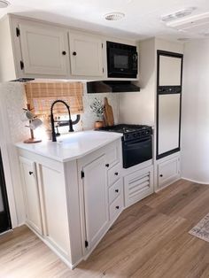 a kitchen with white cabinets and black appliances