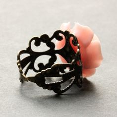 "A pretty shade of peachy pink resin has been used to create a handmade resin rose that has then been set upon an adjustable filigree ring base in your choice of finish in this delicate rose ring that is made to be adjustable from size 6 and up. Flower Size: 19mm To see this ring in all available colors, check here: http://etsy.me/1gr9dLc The base for this handmade ring is adjustable, which makes this delicate rose ring comfortable no matter the size of the wearer's fingers (size 6 and up) as we Pink Rose Design Ring For Gift, Adjustable Pink Flower Ring For Wedding, Handmade Vintage Pink Rings, Pink Flower Ring With Rose Design, Pink Rose Design Flower Ring, Handmade Pink Flower Shaped Rings, Adjustable Pink Flower Shaped Rings, Handmade Adjustable Flower-shaped Rings, Handmade Pink Flower-shaped Rings