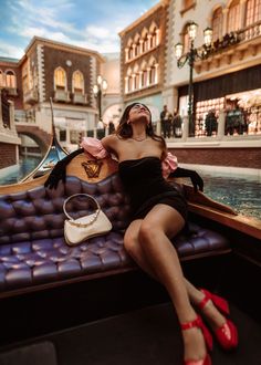 a woman in a black dress is sitting on a boat