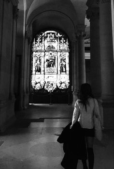 a woman is walking in front of a stained glass window