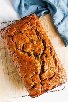 a loaf of bread sitting on top of a cooling rack next to a blue towel