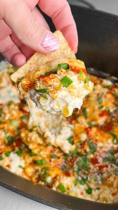 a person scooping some food out of a skillet with a tortilla chip