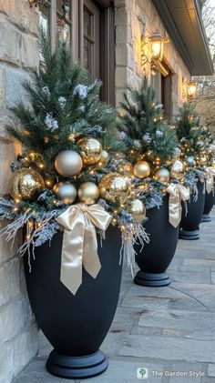 three large black vases with christmas decorations on the outside and gold balls in them