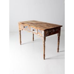 an old wooden table with two drawers on one side and three legs, against a white background