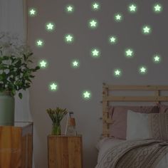 a bed room with a neatly made bed and green stars wall decals on the walls