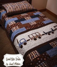 a bed with a train quilt on it and a pillow in the shape of a truck