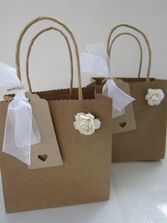 three brown paper bags with white flowers and ribbons tied to the handles are sitting on a table