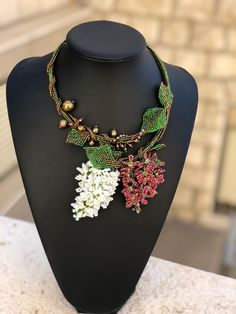 a necklace on a mannequin with beads and flowers