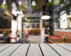 an empty wooden table top in front of a blurry image of a restaurant with tables and chairs