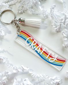 a plastic keychain with the word art on it and a rainbow painted design