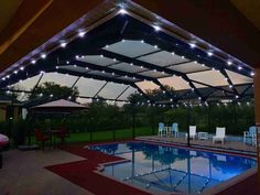 an outdoor pool with lights and chairs around it