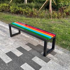 a colorful bench sitting on top of a tiled floor next to a lush green field