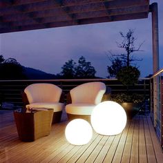 two chairs sitting on top of a wooden deck next to lamps and lightshades