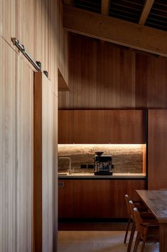 a kitchen with wooden walls and flooring next to a dining table