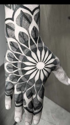 a black and white photo of a person's hand with an intricate design on it