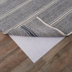 a piece of white paper on top of a wooden floor next to a blue and white checkered blanket