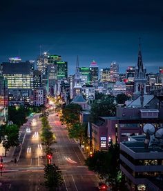 the city skyline is lit up at night, with cars driving on the street and buildings in the background