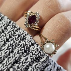 a close up of a person's hand wearing two rings with pearls on them