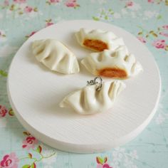 three small pieces of food sitting on top of a white plate next to pink flowers