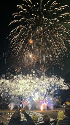 people are taking pictures with their cell phones as fireworks go off in the sky