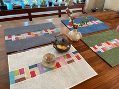 a wooden table topped with place mats and vases filled with flowers on top of it