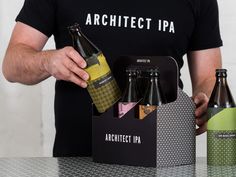 a man is holding two bottles in front of an open box that contains four different types of beer