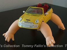 a yellow toy car with a red hat on it's head sitting on a black table