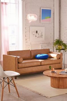 a living room filled with furniture next to a white brick wall and wooden flooring