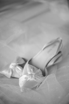 black and white photo of wedding shoes with bows on the bottom, in tulle