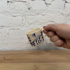 a person is holding a coffee cup in their left hand and pointing it at the wall