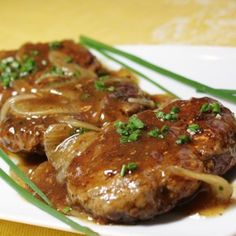 some meat and onions on a white plate with green onions in the center, garnished with parsley