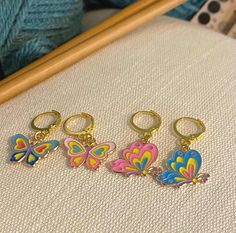 three butterfly keychains sitting on top of a table next to yarn and knitting needles